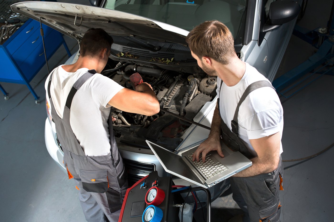 Due meccanici al lavoro sul vano motore con la strumentazione di diagnosi
