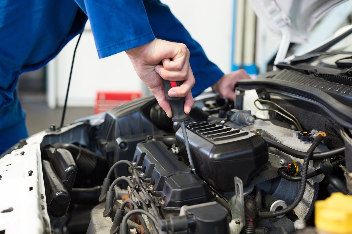 Meccanico al lavoro sul motore di un'auto con il cofano aperto